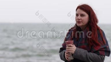 一个留着红色长发的小女孩，穿着一件保暖外套和羊毛围巾，拿着一个金属热水瓶，上面放着一杯热饮料。 头发